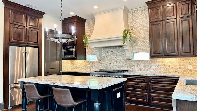 4818 Lake Village Dr, Fulshear, TX 77441 - kitchen featuring appliances with stainless steel finishes, a kitchen island, dark wood finished floors, premium range hood, and dark brown cabinetry