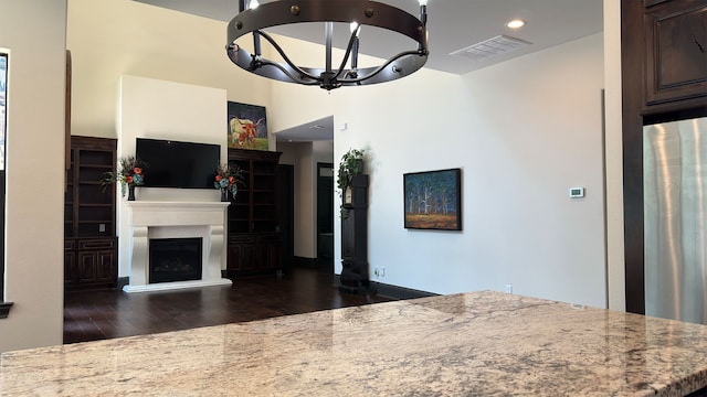4818 Lake Village Dr, Fulshear, TX 77441 - kitchen featuring wood finished floors, stone countertops, a fireplace with raised hearth, a chandelier, and dark brown cabinets