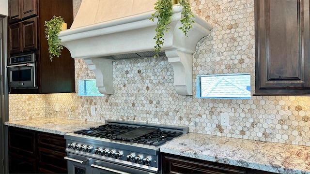 4818 Lake Village Dr, Fulshear, TX 77441 - kitchen with appliances with stainless steel finishes, dark brown cabinets, ventilation hood, and backsplash