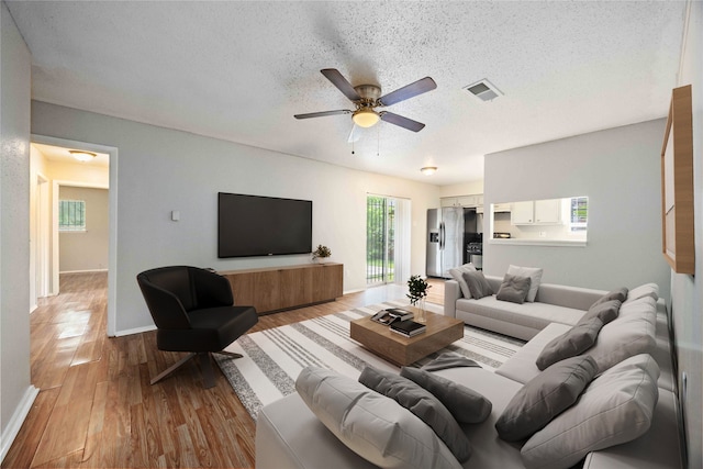 11750 Murr Way, Houston, TX 77048 - living room with a textured ceiling, light wood-style flooring, ceiling fan, and baseboards