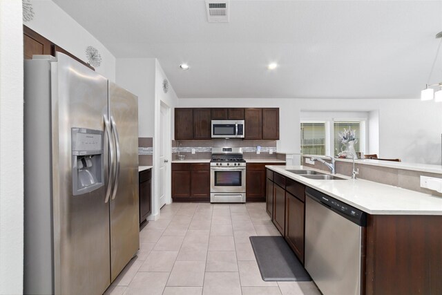6815 Bardsdale Ct, Rosharon, TX 77583 - kitchen with stainless steel appliances, a sink, light countertops, light tile patterned floors, and dark brown cabinetry