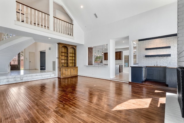 12151 Maple Rock Dr, Houston, TX 77077 - unfurnished living room with high vaulted ceiling, a sink, wood finished floors, baseboards, and arched walkways