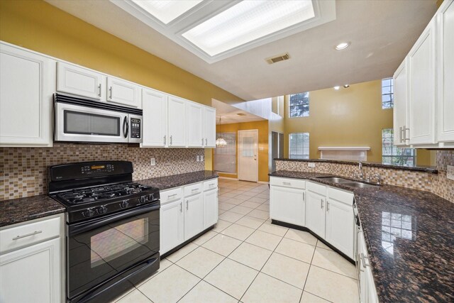 19119 Timber Trace Dr, Humble, TX 77346 - kitchen with stainless steel microwave, black range with gas cooktop, a sink, backsplash, and white cabinetry