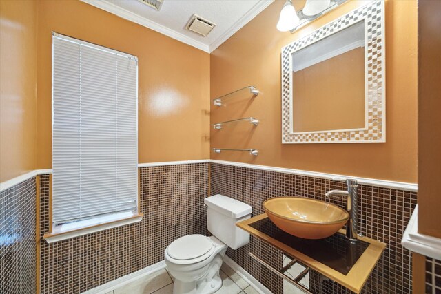 19119 Timber Trace Dr, Humble, TX 77346 - bathroom with a sink, tile walls, ornamental molding, a wainscoted wall, and toilet