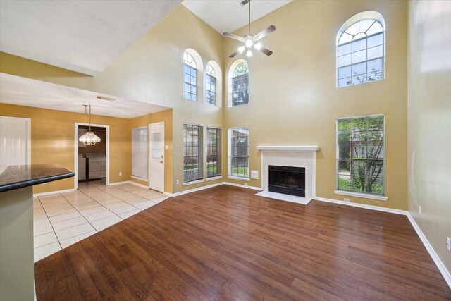 19119 Timber Trace Dr, Humble, TX 77346 - unfurnished living room featuring light wood-type flooring, a fireplace with flush hearth, a ceiling fan, a high ceiling, and baseboards