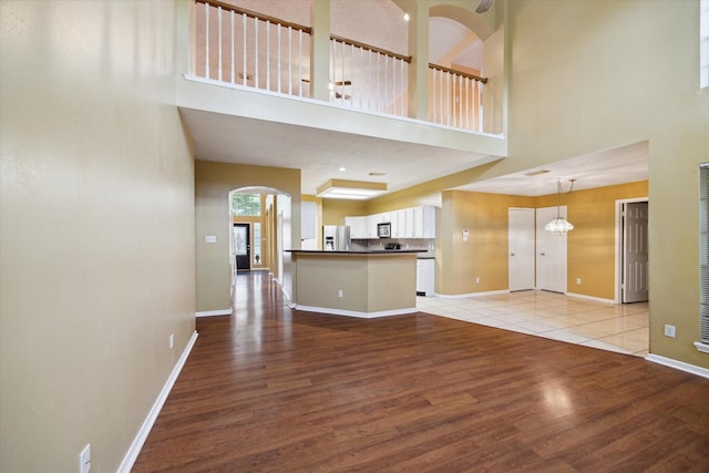 19119 Timber Trace Dr, Humble, TX 77346 - unfurnished living room featuring a towering ceiling, light wood-style floors, baseboards, and arched walkways