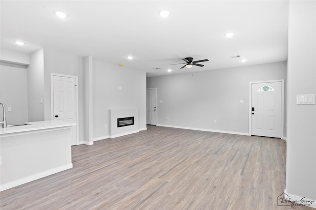 7983 Ethel St, Houston, TX 77028 - unfurnished living room with ceiling fan, recessed lighting, light wood finished floors, a glass covered fireplace, and baseboards