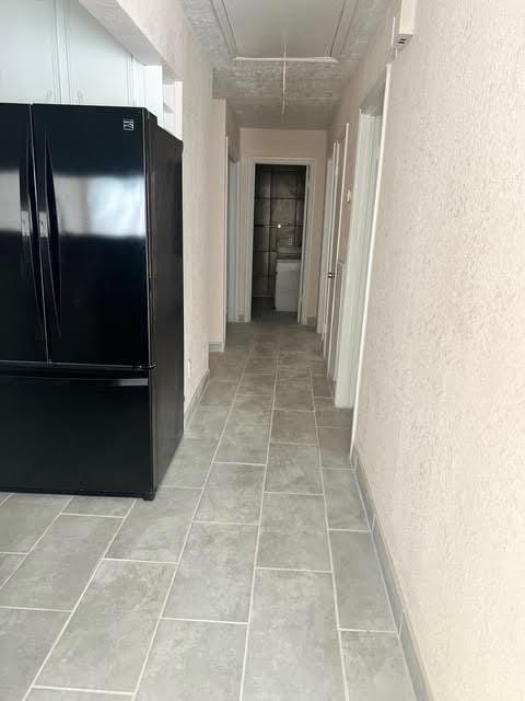 7847 Creekbend Dr, Houston, TX 77071 - hallway featuring attic access, a textured wall, and light tile patterned floors