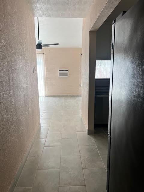 7847 Creekbend Dr, Houston, TX 77071 - hall with tile patterned floors, a wall mounted air conditioner, and a textured wall