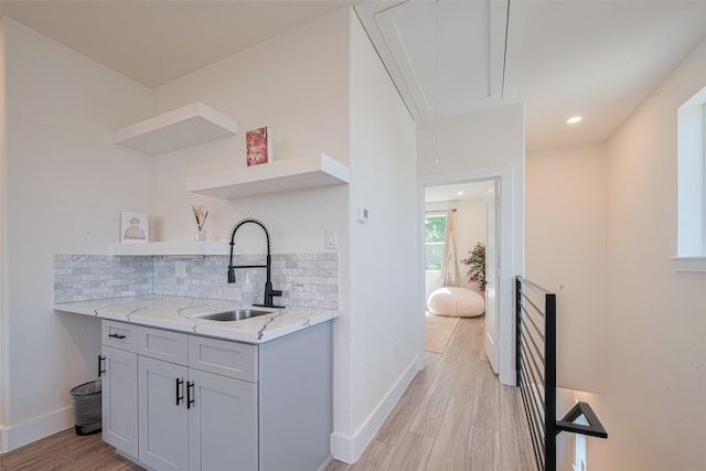 2909 Nagle St, Houston, TX 77004 - kitchen with open shelves, a sink, tasteful backsplash, light wood finished floors, and light stone counters