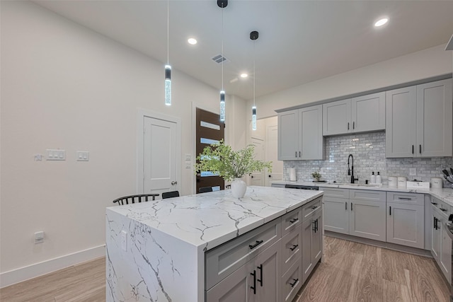 2909 Nagle St, Houston, TX 77004 - kitchen with gray cabinets, a sink, backsplash, a center island, and recessed lighting