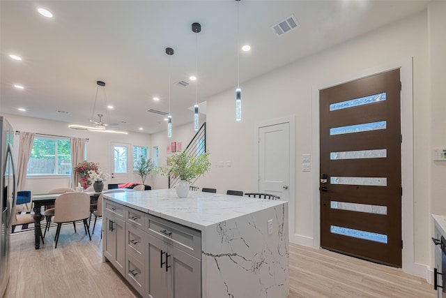 2909 Nagle St, Houston, TX 77004 - kitchen with a kitchen island, light wood-type flooring, decorative light fixtures, light stone countertops, and recessed lighting