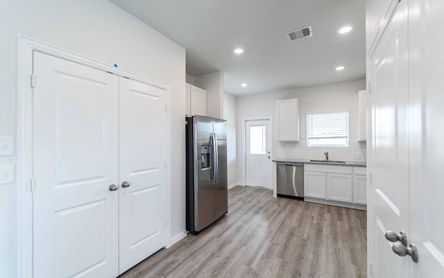 4350 Maple Root Ln, Pinehurst, TX 77362 - kitchen featuring stainless steel appliances, light wood-style flooring, white cabinets, tasteful backsplash, and recessed lighting
