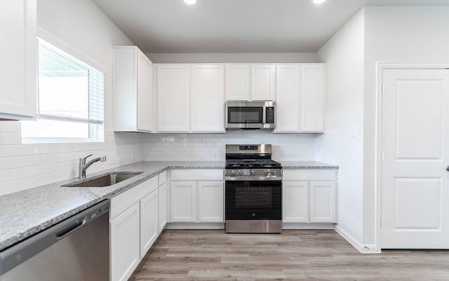 4350 Maple Root Ln, Pinehurst, TX 77362 - kitchen with appliances with stainless steel finishes, white cabinets, tasteful backsplash, light stone counters, and recessed lighting
