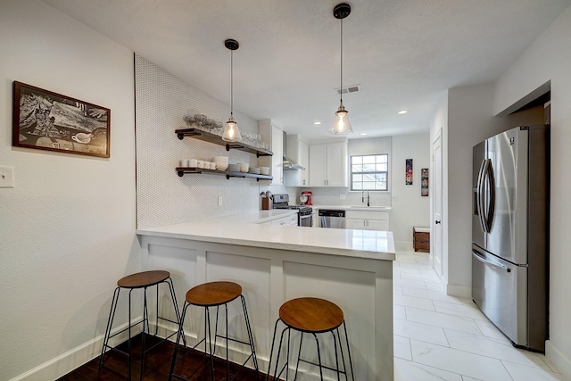 5120 Leeland St, Houston, TX 77023 - kitchen featuring stainless steel appliances, a peninsula, a sink, light countertops, and a kitchen breakfast bar