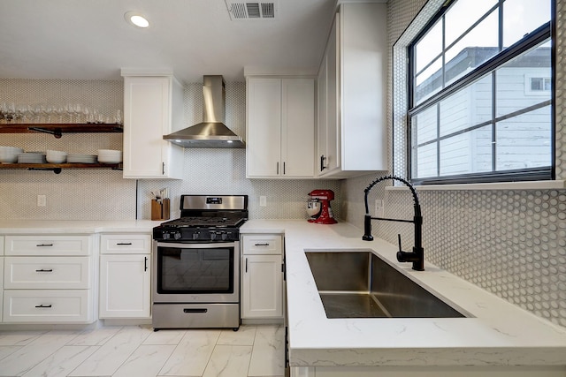 5120 Leeland St, Houston, TX 77023 - kitchen featuring gas stove, wall chimney exhaust hood, a sink, light marble finish floors, and white cabinets