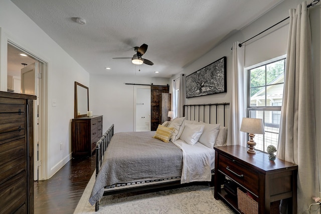 5120 Leeland St, Houston, TX 77023 - bedroom featuring a barn door, wood finished floors, baseboards, ceiling fan, and recessed lighting