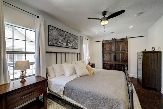5120 Leeland St, Houston, TX 77023 - bedroom with a barn door, multiple windows, dark wood-type flooring, recessed lighting, and a textured ceiling
