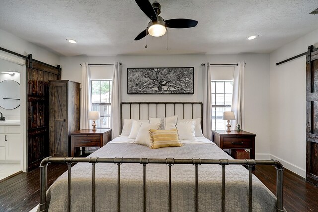 5120 Leeland St, Houston, TX 77023 - bedroom with a barn door, wood-type flooring, a textured ceiling, baseboards, and recessed lighting