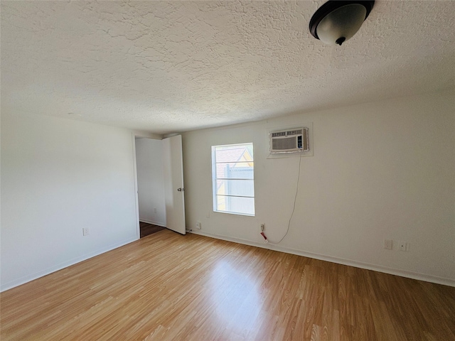 5120 Leeland St, Houston, TX 77023 - unfurnished room featuring light wood-type flooring, baseboards, a textured ceiling, and a wall unit AC
