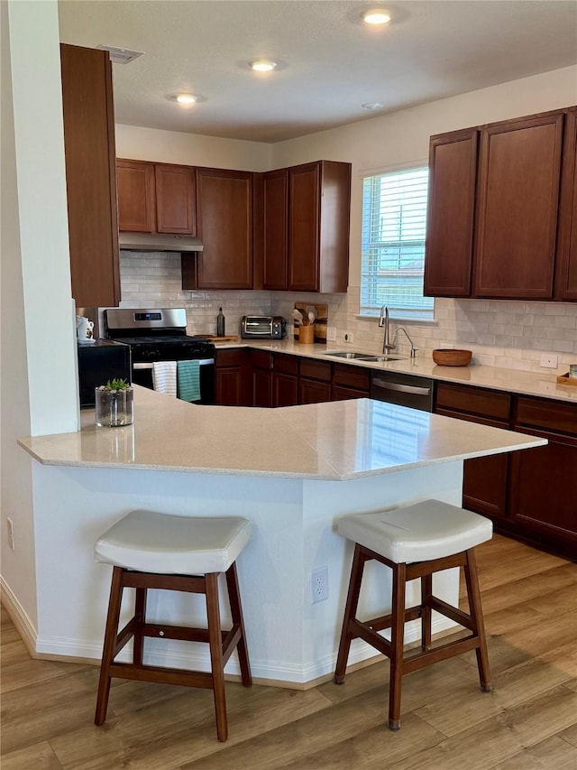 2900 Glint Peak Ct, Katy, TX 77493 - kitchen featuring stainless steel appliances, a kitchen bar, a sink, light countertops, and backsplash