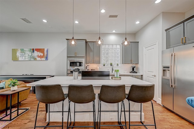 804 Paige St, Houston, TX 77003 - kitchen with stainless steel appliances, light countertops, gray cabinets, a kitchen breakfast bar, and recessed lighting