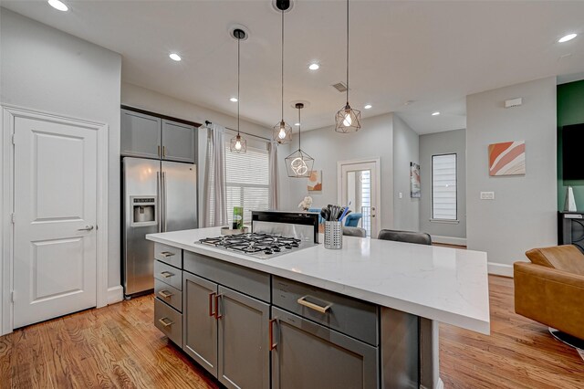 804 Paige St, Houston, TX 77003 - kitchen featuring stainless steel appliances, gray cabinetry, open floor plan, light wood finished floors, and pendant lighting