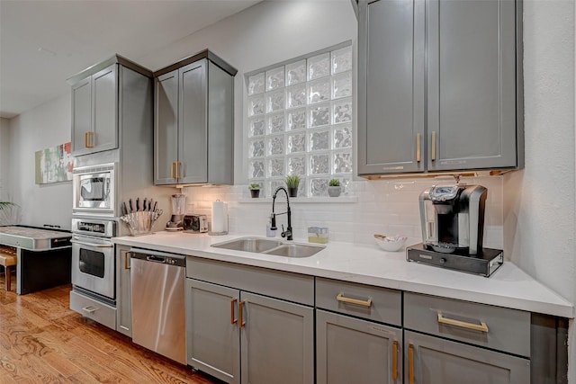 804 Paige St, Houston, TX 77003 - kitchen featuring stainless steel appliances, gray cabinetry, a sink, and light wood-style floors