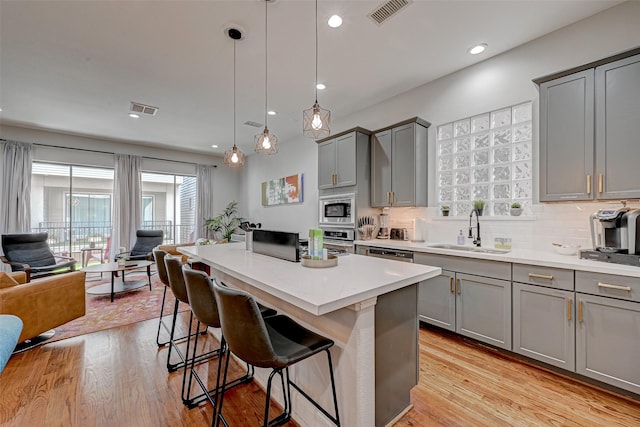 804 Paige St, Houston, TX 77003 - kitchen featuring gray cabinetry, a sink, appliances with stainless steel finishes, a kitchen breakfast bar, and a kitchen island