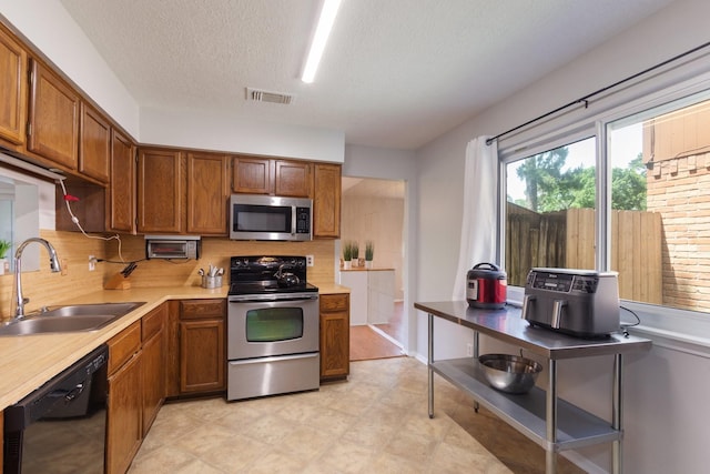 4315 Stallion Brook Ln, Spring, TX 77388 - kitchen featuring stainless steel appliances, light countertops, decorative backsplash, a textured ceiling, and brown cabinetry