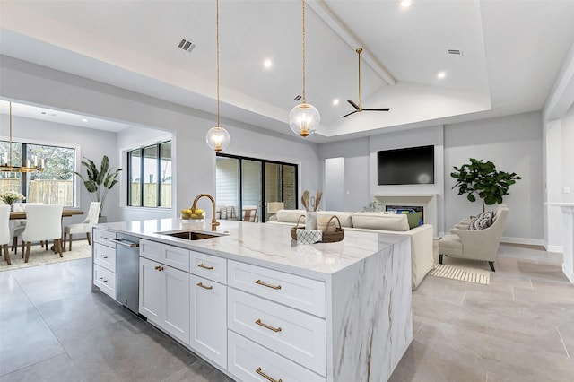 9606 Maribelle Way, Houston, TX 77055 - kitchen with a sink, white cabinets, a center island with sink, a glass covered fireplace, and light stone counters