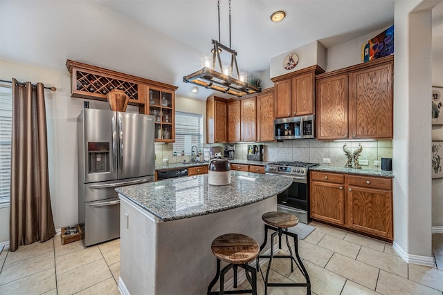 4818 Connor Dr, Baytown, TX 77521 - kitchen featuring appliances with stainless steel finishes, tasteful backsplash, brown cabinets, and a kitchen island