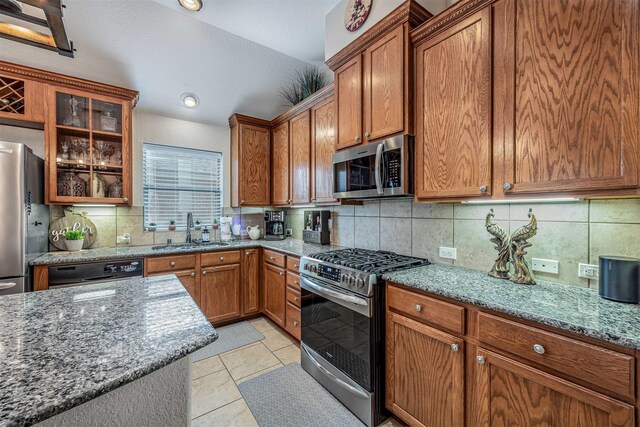4818 Connor Dr, Baytown, TX 77521 - kitchen featuring appliances with stainless steel finishes, a sink, light stone countertops, brown cabinets, and tasteful backsplash