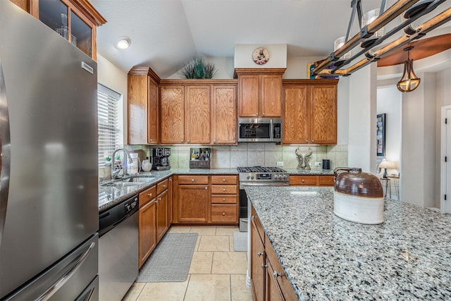 4818 Connor Dr, Baytown, TX 77521 - kitchen featuring appliances with stainless steel finishes, a sink, brown cabinets, vaulted ceiling, and tasteful backsplash