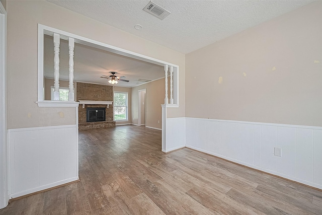 5118 Forest Trl, Baytown, TX 77521 - unfurnished living room featuring a ceiling fan, wood finished floors, a wainscoted wall, a fireplace, and a textured ceiling