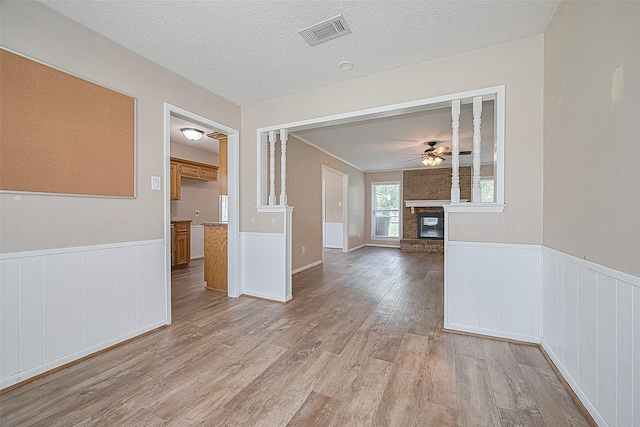 5118 Forest Trl, Baytown, TX 77521 - unfurnished living room with wood finished floors, ceiling fan, a brick fireplace, a wainscoted wall, and a textured ceiling