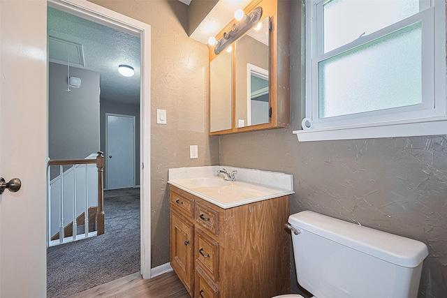 5118 Forest Trl, Baytown, TX 77521 - half bathroom featuring a textured wall, wood finished floors, toilet, vanity, and a textured ceiling
