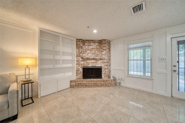 7838 Vickijohn Dr, Houston, TX 77071 - unfurnished living room featuring built in shelves, a textured ceiling, light tile patterned floors, a brick fireplace, and a decorative wall