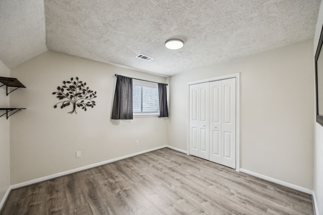 233 Magnolia Way, Huntsville, TX 77320 - unfurnished bedroom with wood finished floors, a closet, baseboards, and a textured ceiling