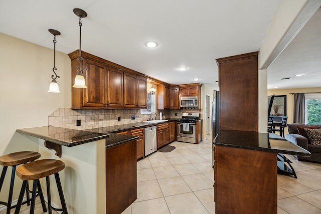 233 Magnolia Way, Huntsville, TX 77320 - kitchen with appliances with stainless steel finishes, a peninsula, a sink, a kitchen breakfast bar, and decorative backsplash