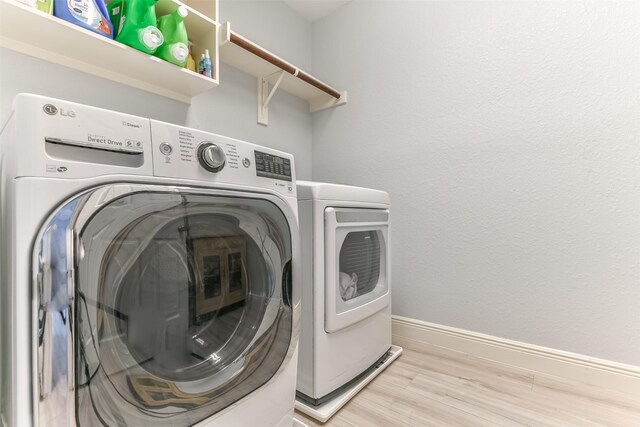 1753 Cranston Grove Dr, Dickinson, TX 77539 - laundry room with washing machine and dryer, light wood-style flooring, and baseboards