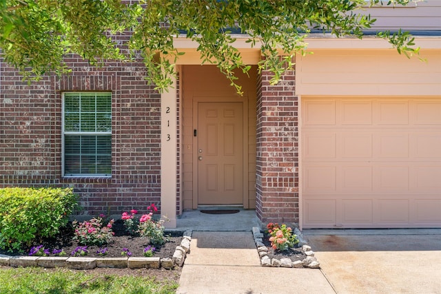 213 Splintered Arrow Dr, La Marque, TX 77568 - view of exterior entry featuring brick siding, an attached garage, and concrete driveway