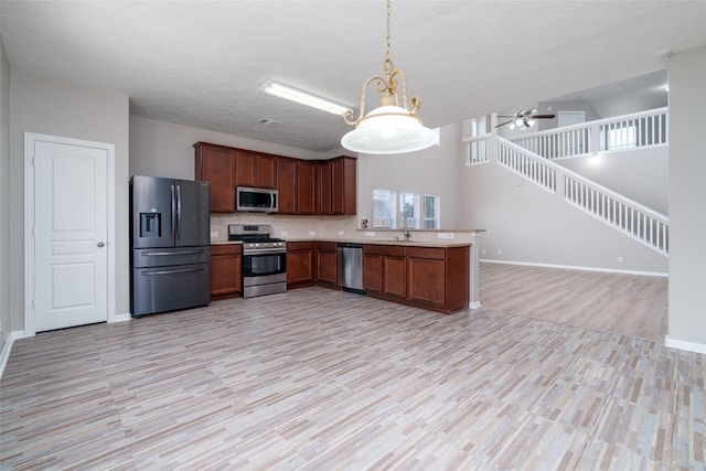 213 Splintered Arrow Dr, La Marque, TX 77568 - kitchen with stainless steel appliances, open floor plan, light wood finished floors, a sink, and light countertops