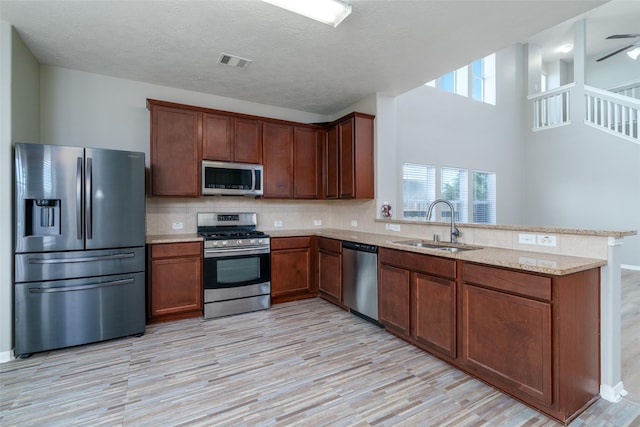 213 Splintered Arrow Dr, La Marque, TX 77568 - kitchen with appliances with stainless steel finishes, a peninsula, light wood finished floors, a sink, and tasteful backsplash