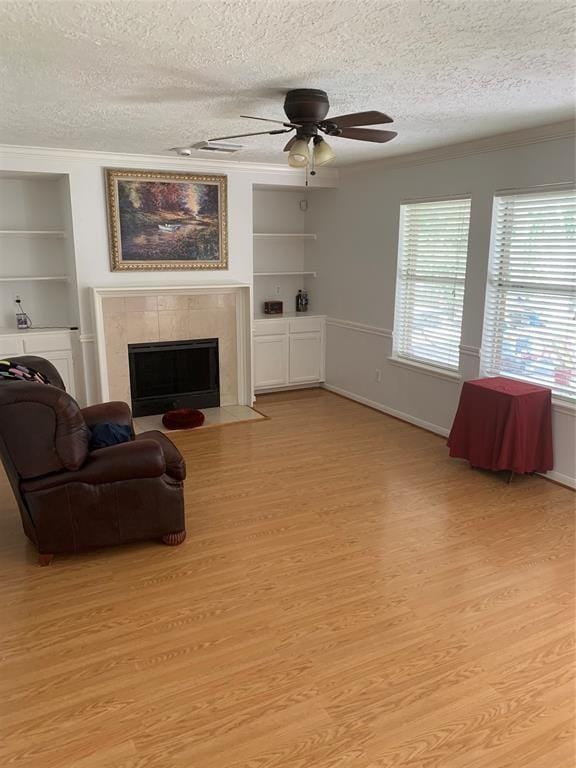 10702 Allens Landing Dr, Houston, TX 77065 - living room featuring a textured ceiling, built in shelves, light wood-style floors, plenty of natural light, and crown molding