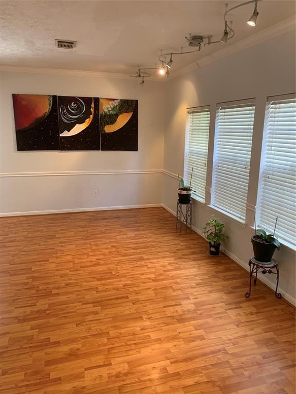 10702 Allens Landing Dr, Houston, TX 77065 - empty room featuring ornamental molding, rail lighting, light wood-style flooring, and baseboards