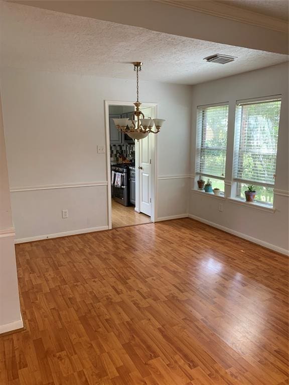 10702 Allens Landing Dr, Houston, TX 77065 - unfurnished room with a chandelier, light wood-style flooring, baseboards, and a textured ceiling