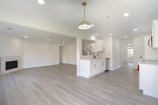 21511 Pepperberry Trl, Spring, TX 77388 - kitchen with stainless steel dishwasher, light countertops, open floor plan, light wood finished floors, and white cabinets