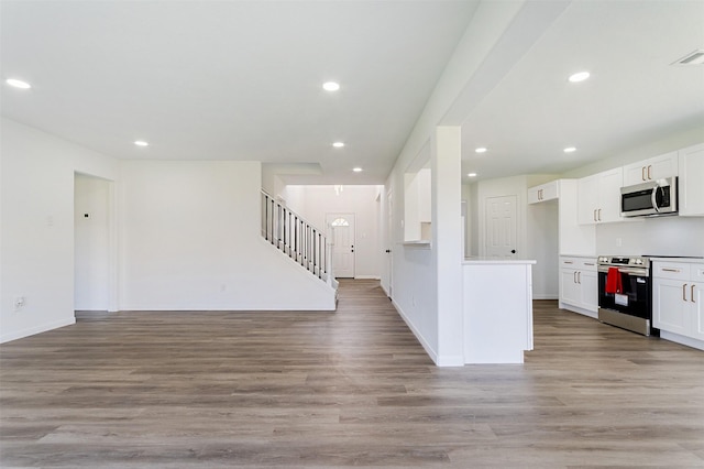 21511 Pepperberry Trl, Spring, TX 77388 - kitchen with appliances with stainless steel finishes, open floor plan, white cabinets, light wood-style flooring, and recessed lighting