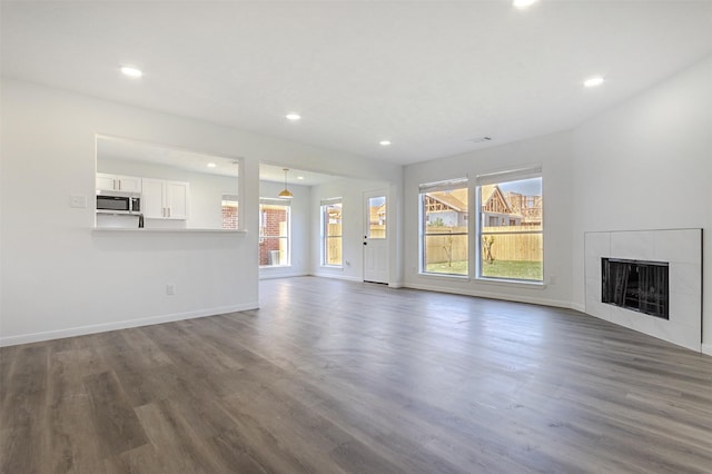 21511 Pepperberry Trl, Spring, TX 77388 - unfurnished living room with dark wood finished floors, baseboards, recessed lighting, and a tiled fireplace